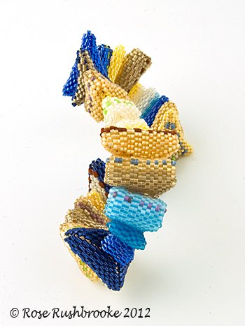 Bangle inspired by Rabbit Hole fractal art quilt - continuous peyote stitch beaded beads, shown sideways to emphasise twisted triangles. Image copyright &copy; Rose Rushbrooke.